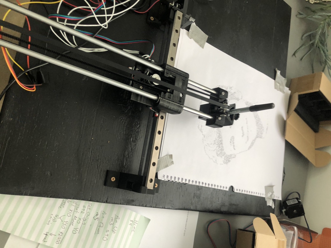 Mid-portrait: the pen carriage working its way across a taped-down page